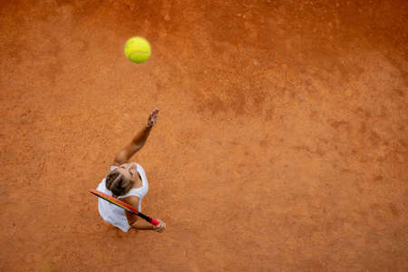 Professional tennis player playing tennis on a clay tennis court on a sunny dayの写真素材