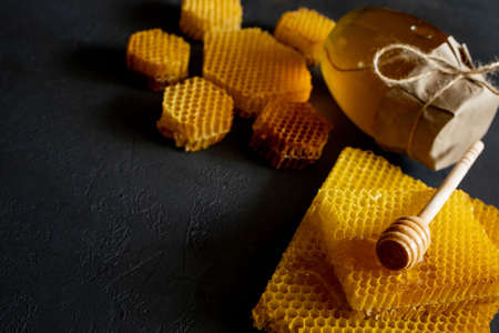 Honey in a jar and a honeycomb. On a black wooden background. Free space for text. Top viewの写真素材