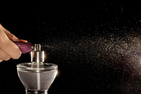Spraying perfume bottle glass on a black background.の写真素材