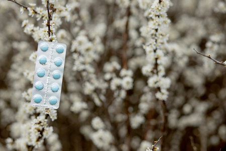 Allergy pills against the blooming plants background.