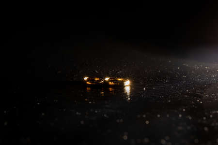 Two golden wedding rings on black backgroundの写真素材