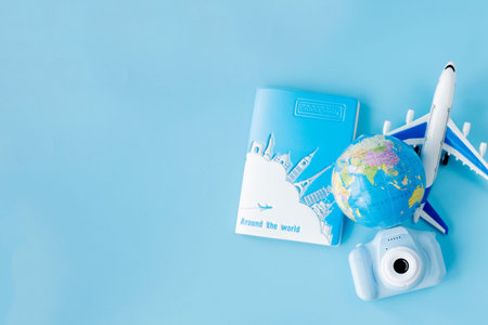 Flight tickets with passports, camera, model of airplane and globe on blue background. Summer or...
