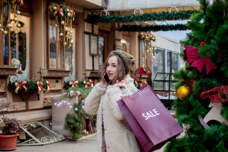 Happy girl holds paperbags with symbol of sale in the stores with sales at Christmas, around the city. Concept of shopping, holidays, happiness, Christmas Salesの写真素材