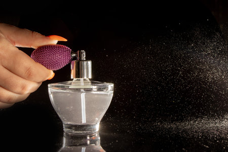 Spraying perfume bottle glass on a black background.