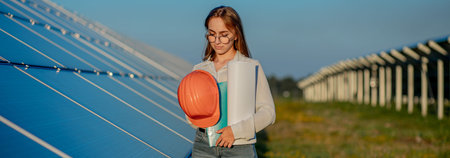 Beautiful young engineer standing near solar panels outdoors, Green Energy Concept.