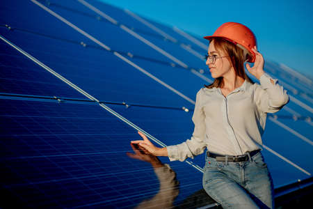 Beautiful young engineer standing near solar panels outdoors, Green Energy Concept.の写真素材
