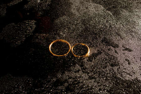 Two golden wedding rings on black backgroundの写真素材