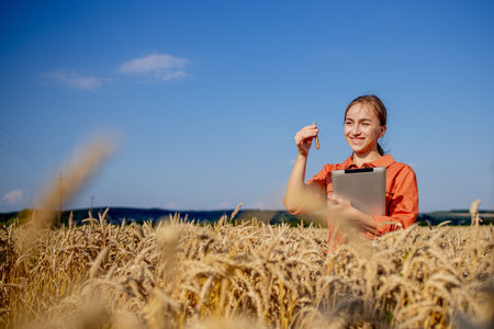Farmer researching plant in wheat field. In his hand he holds a glass tube containing test substance...