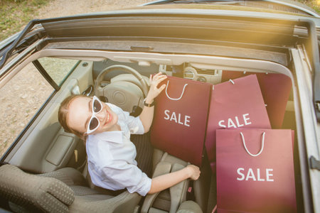 A girl with shopping bags is driving a car, concept of discounts and shopping, top view.