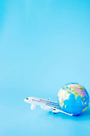 Airplane and globe on blue background. Summer or vacation concept. Copy space.の写真素材