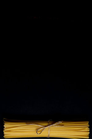 Dry spaghetti stands on a black background. Cooking concept. Space for text