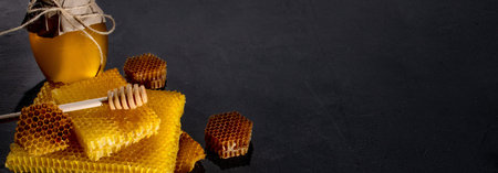 Honey in a jar and a honeycomb. On a black wooden background. Free space for text. Top view