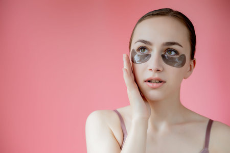 Head shot portrait close up smiling young woman with under eye moisturizing patches mask looking at camera enjoying skincare procedureの写真素材