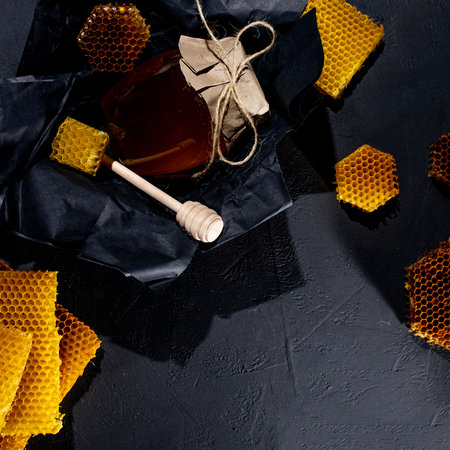 Honey background. Natural honey comb and a wooden spoon. On black rustic tableの写真素材