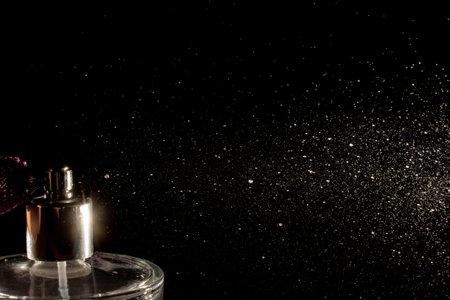 Spraying perfume bottle glass on a black background.