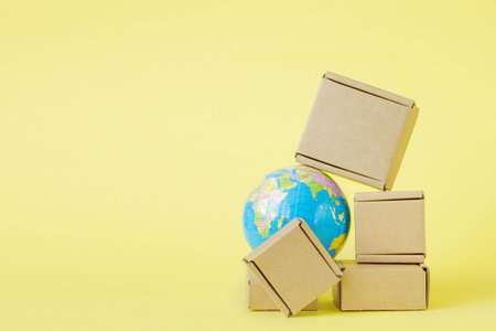 Earth globe is surrounded by boxes. Global business and international transportation of goods products. Shipping freight, world trade and economics. Distribution, import export. Commodity turnover.の写真素材