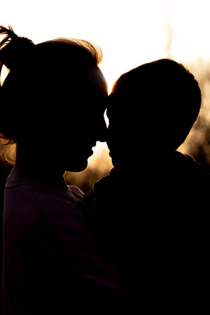 Silhouette of a mother and son playing outdoors at sunset. Mother's day concept.の写真素材