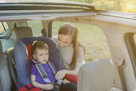 Mother gives the phone little boy sitting in a car seat. Safety of transportation of children.の写真素材