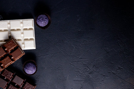 Three types of chocolate - black, milk and white with luxury handmade chocolates on a black...
