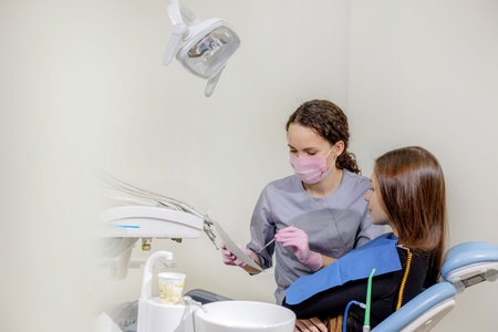 Dentist explaining the details of a x-ray teeth picture to his patient in clinic. Oral care,...