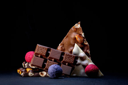 Chocolate candy truffle with chocolate pieces and flying cocoa powder on a dark background.