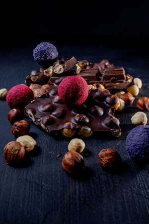 Chocolate candy truffle with chocolate pieces and flying cocoa powder on a dark background.の写真素材