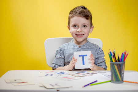 Happy smiling little preschool boy shows letters at home making homework at the morning before the school starts. English learning for kids.の写真素材