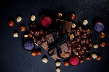 Chocolate candy truffle with chocolate pieces and flying cocoa powder on a dark background.の写真素材
