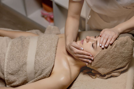 Relaxing massage. Woman receiving head massage at spa salon, side view.の写真素材