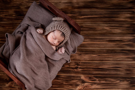 Newborn baby, beautiful infant lies in brown fur blanket on wood background, 10 days old girl...