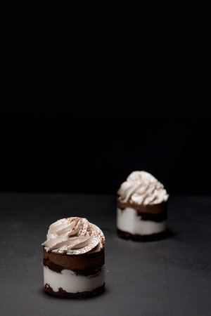Petit fours or mini chocolate crepe cakes with chocolate on black background.