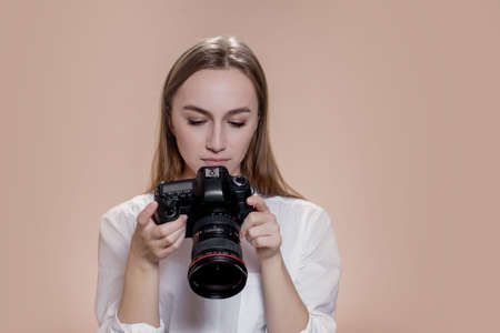 Close up portrait of woman photographer with camera taking pictures with digital camera on brown background.の写真素材