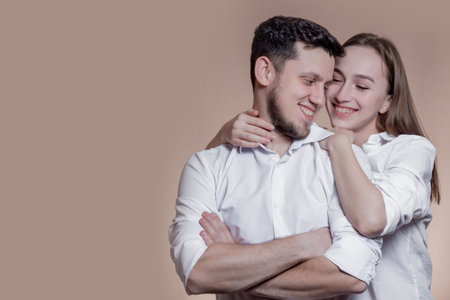 Couple in love looking at each other with love and smiling on brown background. Attractive people,...