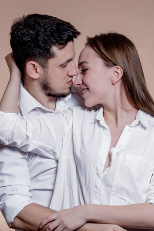 Couple in love looking at each other with love and smiling on brown background. Attractive people,...
