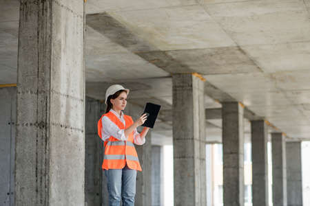 Construction concept of Engineer or Architect working at Construction Site. A woman with a tablet at a construction site. Bureau of Architectureの写真素材