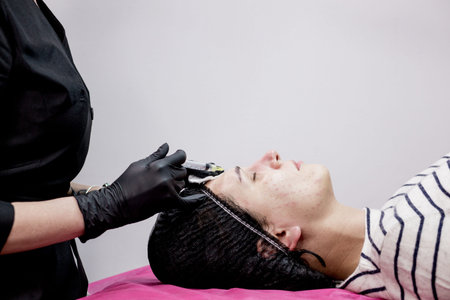 Face mesotherapy procedure in a beauty salon. Beautician doctor makes injections into the skin of...