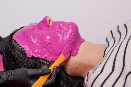 Alginate mask application process. A female hands of a beautician holding spatula. The procedure for...