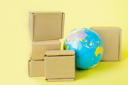 Earth globe is surrounded by boxes. Global business and international transportation of goods products. Shipping freight, world trade and economics. Distribution, import export. Commodity turnover.の写真素材