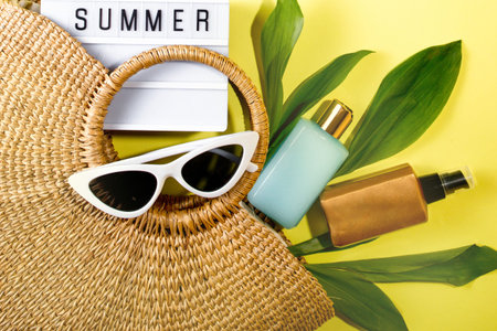 beach bag with beach accessories on a colored background top view. Sunscreen, glasses.