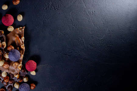 Chocolate bar, crushed pieces of dark chocolate and nuts. Praline Chocolate sweets. Copy space.の写真素材