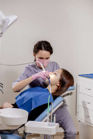 Female dentist checking up patient teeth at dental clinic office. Medicine, dentistry concept. Dental equipment.の写真素材