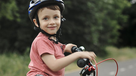 Child riding bicycle on the bike path at rain. Kid in helmet learning to ride at summer. Happy boy riding bike, having fun outdoors on nature. Active sport family leisureの写真素材