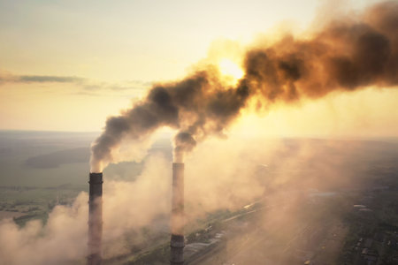Aerial view of coal power plant high pipes with black smoke moving up polluting atmosphere at sunsetの写真素材