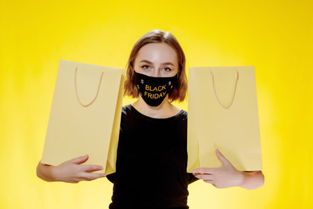 Joyful woman with packages on yellow background, shopping trip. Studio portrait. Black friday sale.