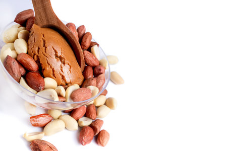 Peanut butter isolated and peanuts in the peel scattered on the white background. Copy space