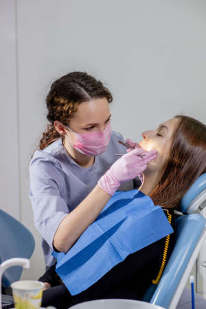 Female dentist checking up patient teeth at dental clinic office. Medicine, dentistry concept. Dental equipment.の写真素材