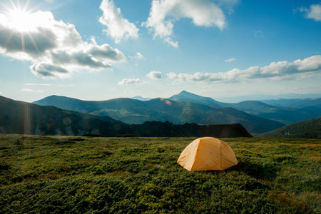 view of tourist tent in mountains at sunrise or sunset. Camping background. Adventure travel active...