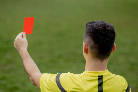 Referee showing a red card to a displeased football or soccer player while gaming. Concept of sport, rules violation, controversial issues, obstacles overcomingの写真素材