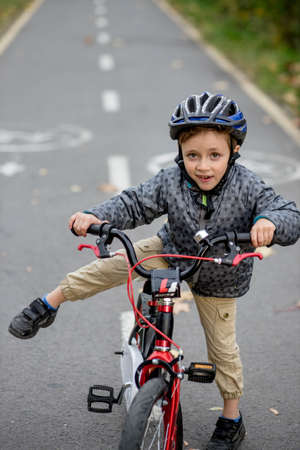 Little boy in a helmet on a bicycle rides on a bike path in the park.の写真素材