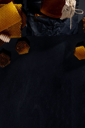 Honey in a jar and a honeycomb. On a black wooden background. Free space for text. Top viewの写真素材